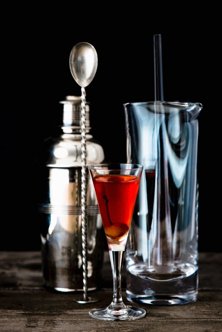 A glass of homemade cherry brandy with bar utensils