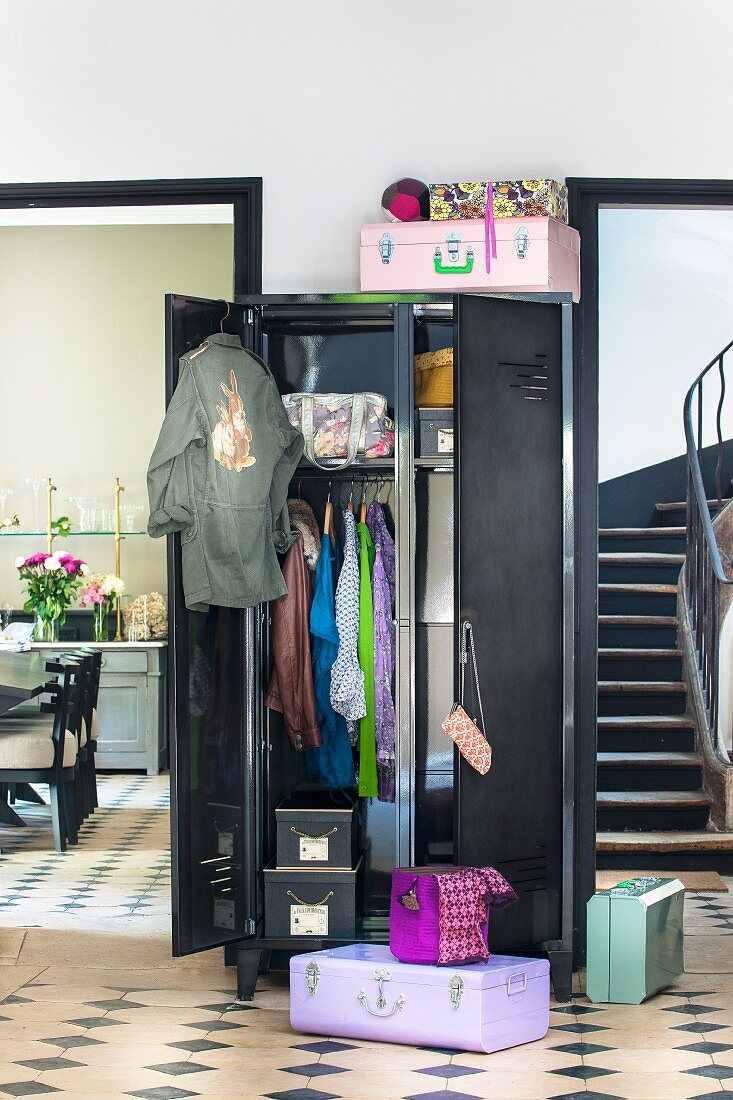 Black locker with open door in hallway between staircase and dining area