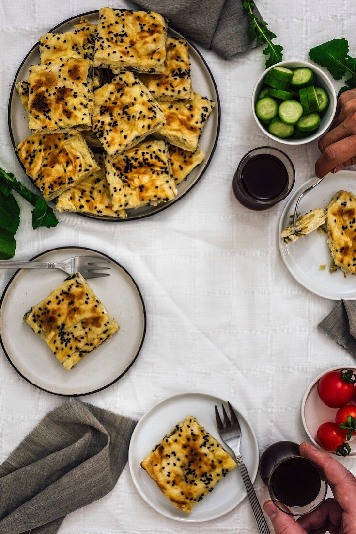 A woman and a man having phyllo pastry stuffed with cheese and herbs and Turkish tea