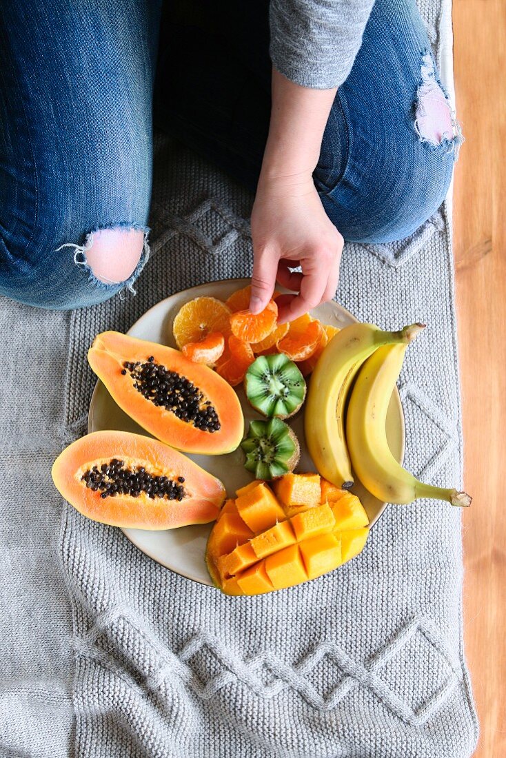 Female sitting on bed and serving fresh fruit