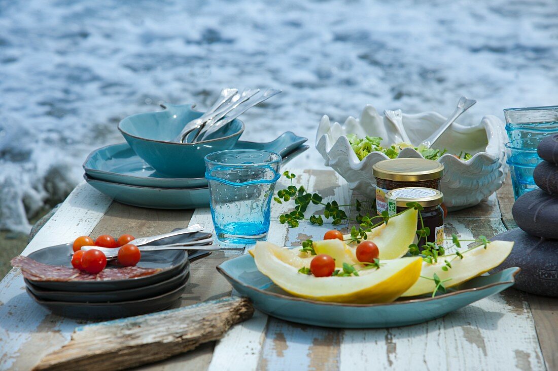 Picknick am Meer mit Melone, Kirschtomaten, Salat, Wurst und Feigenmarmelade