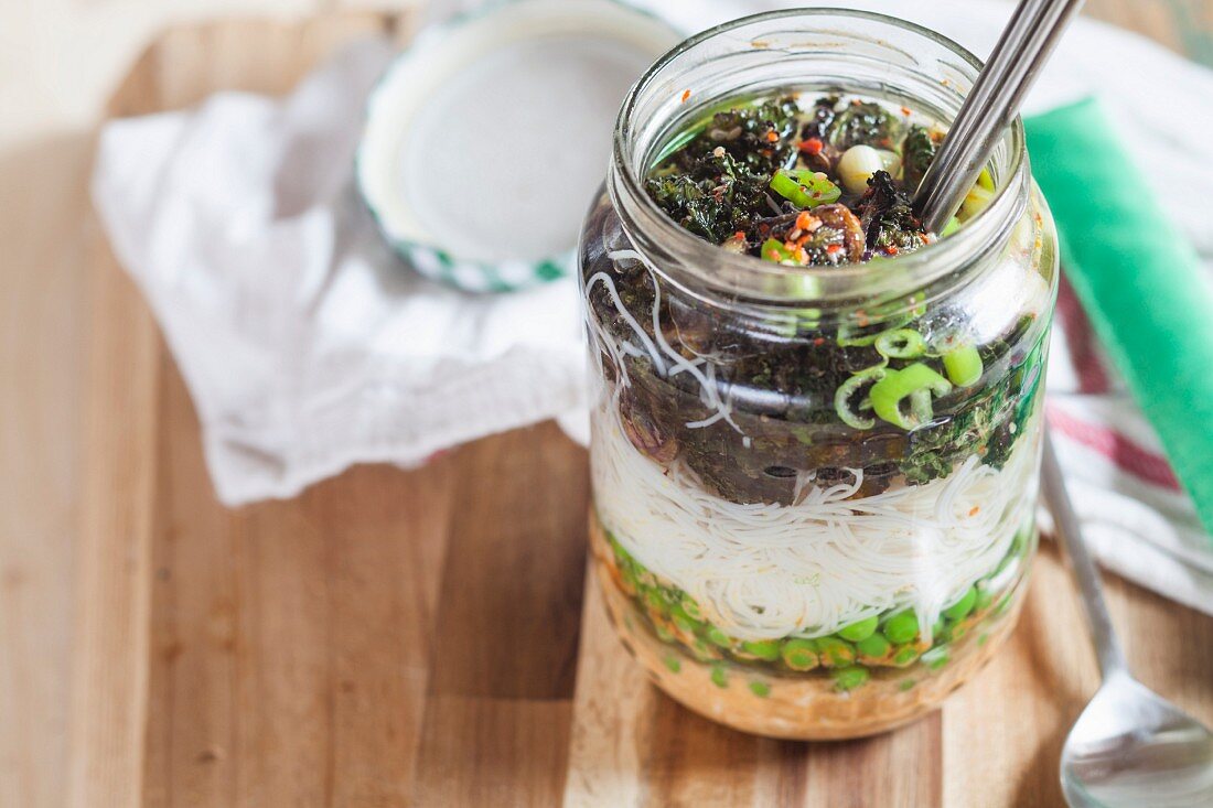 Vegane DIY-Instantsuppe Thai-Style mit Erdnuss-Chili-Paste, Erbsen, Glasnudeln, Frühlingszwiebeln und Rosenkohl, mit Wasser aufgegossen