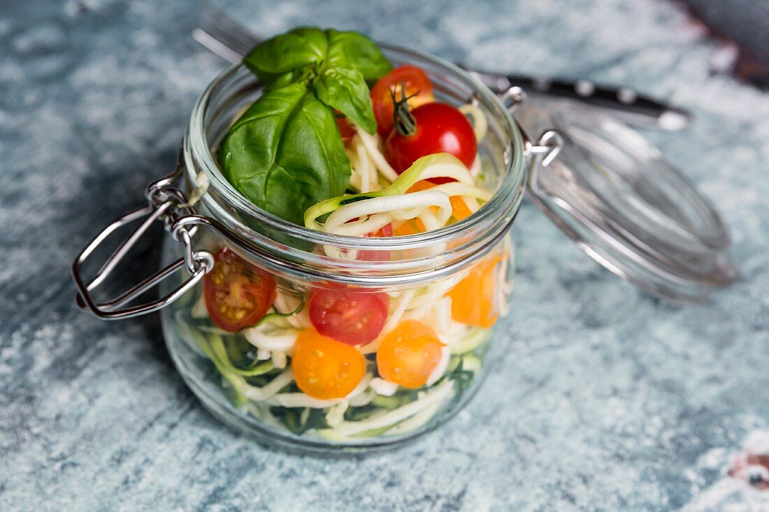 Zoodles (Zucchinispaghetti) im Glas mit Tomaten und Basilikum