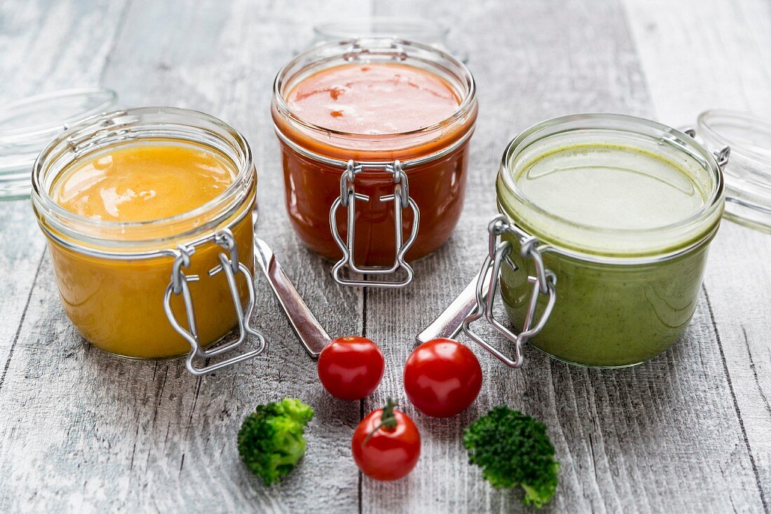 Verschiedene bunte Suppen im Glas (Brokkolisuppe, Tomatensuppe, Kürbissuppe)