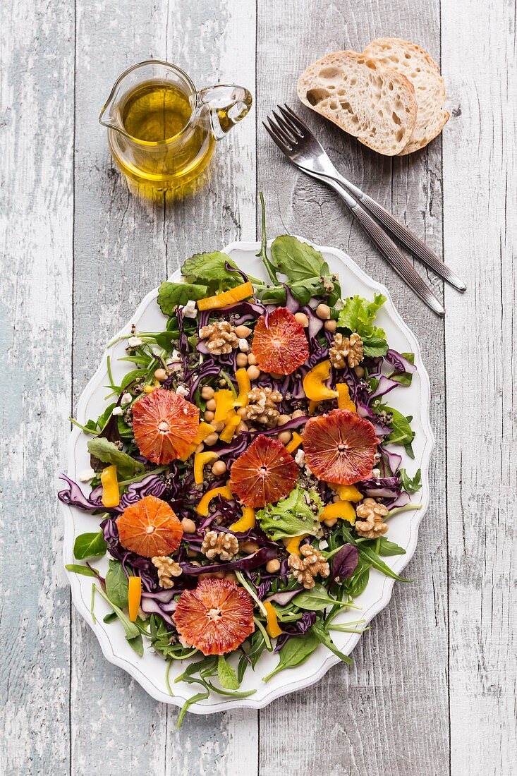 A salad platter with quinoa, chickpeas, yellow pepper, walnuts, red cabbage and blood orange