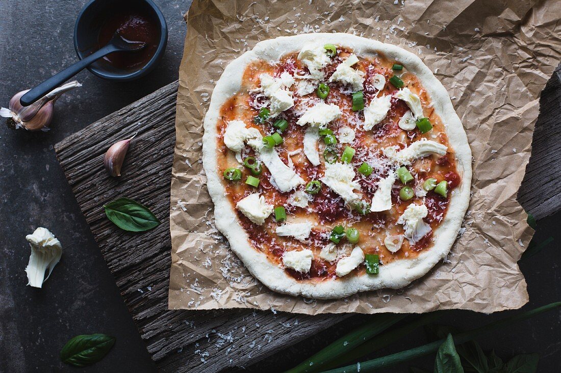 Homemade unbaked pizza with tomato, bocconcini and basil