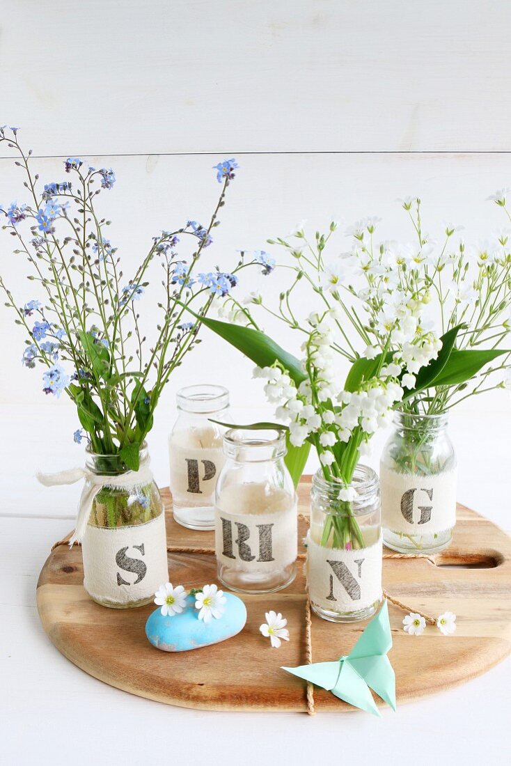Spring flowers in jars decorated with ribbons and letters