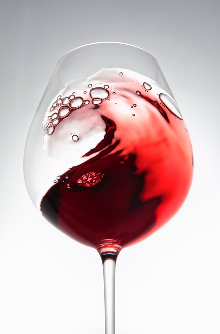 Red wine creating a wave in a glass