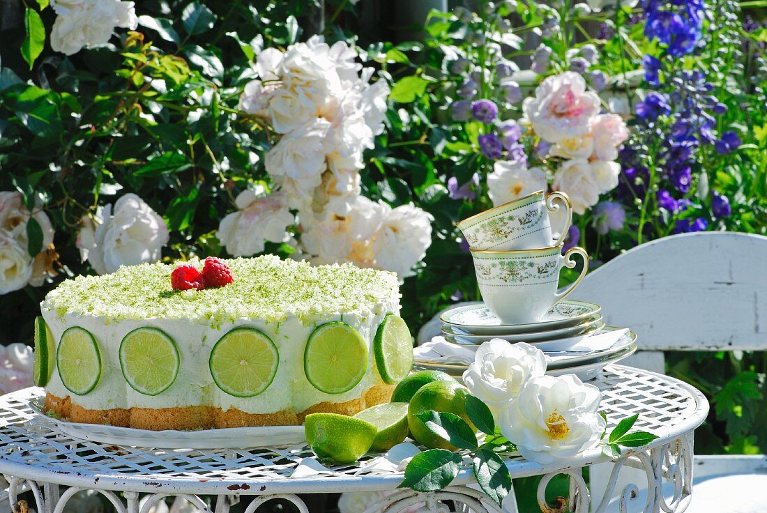 Lime cake with tea cups and flowers on a garden table