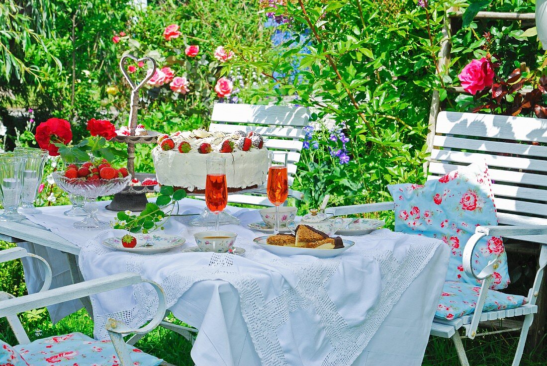 Romantisch gedeckter Kaffeetisch mit Erdbeertorte im sommerlichen Garten