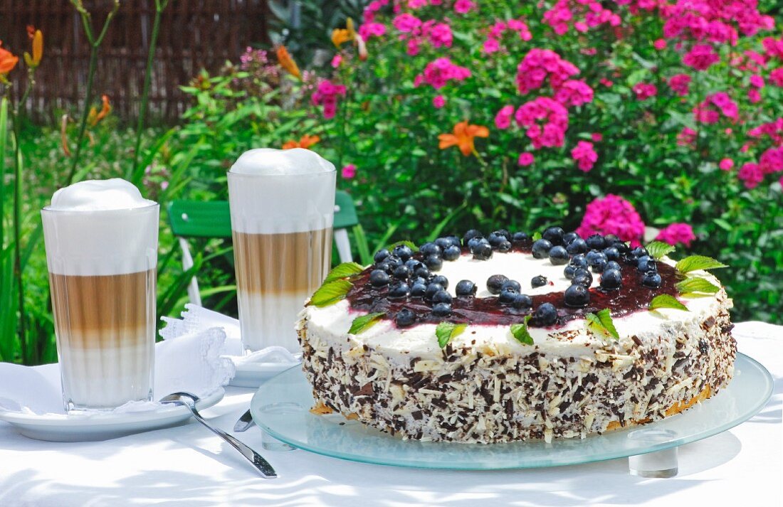 Blueberry and mascarpone pie with latte macchiatos on a table outdoors