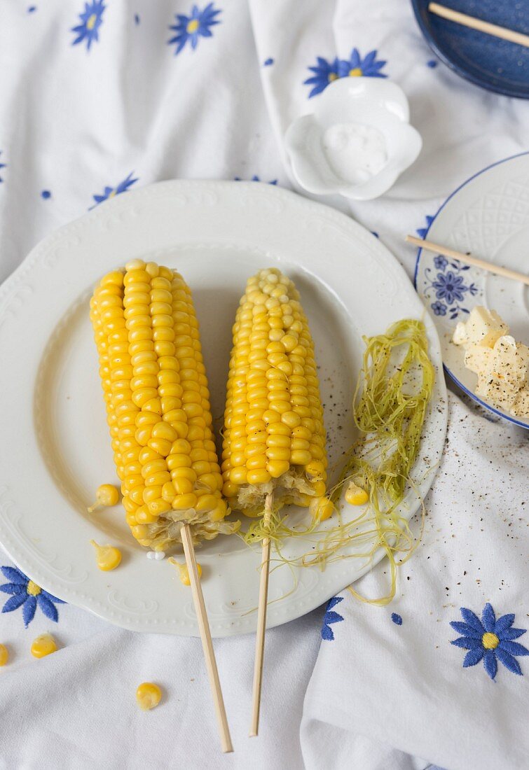 Zwei Maiskolbenspiesse mit Butter und Salz