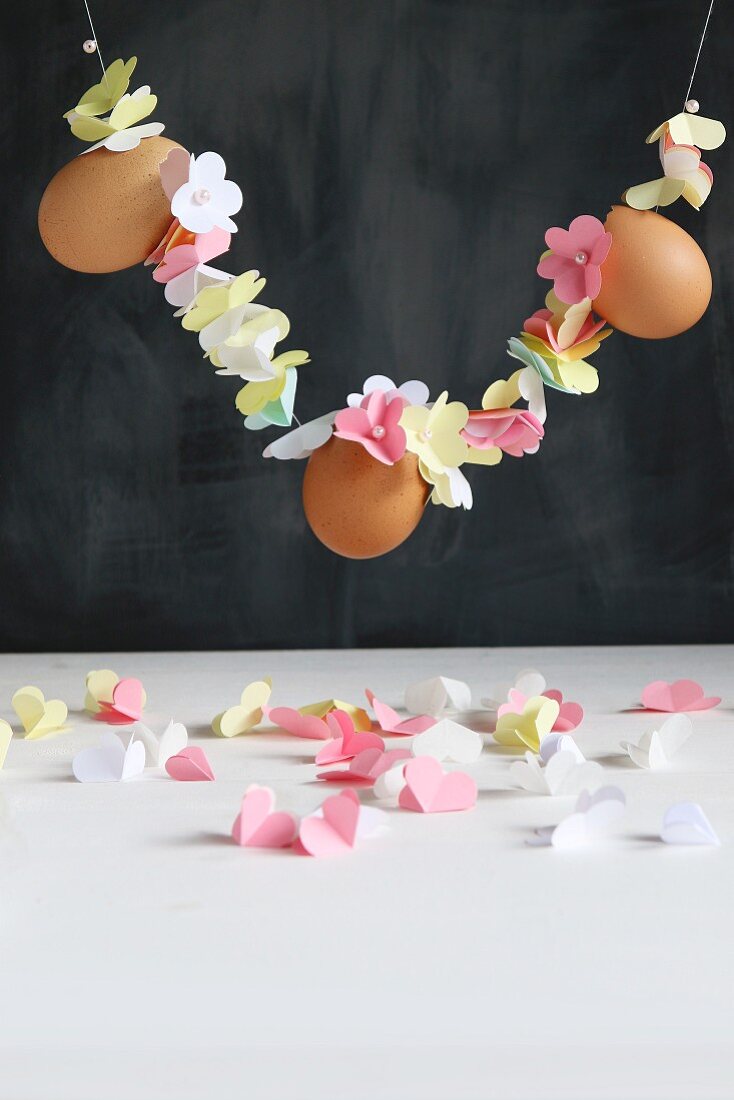 Girlande aus aufgefädelten Papierblüten und Eiern
