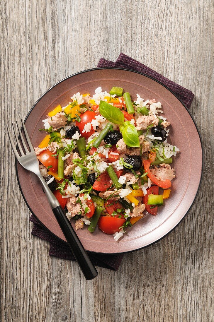 A salad with tuna, rice, tomatoes, beans, peppers and olives