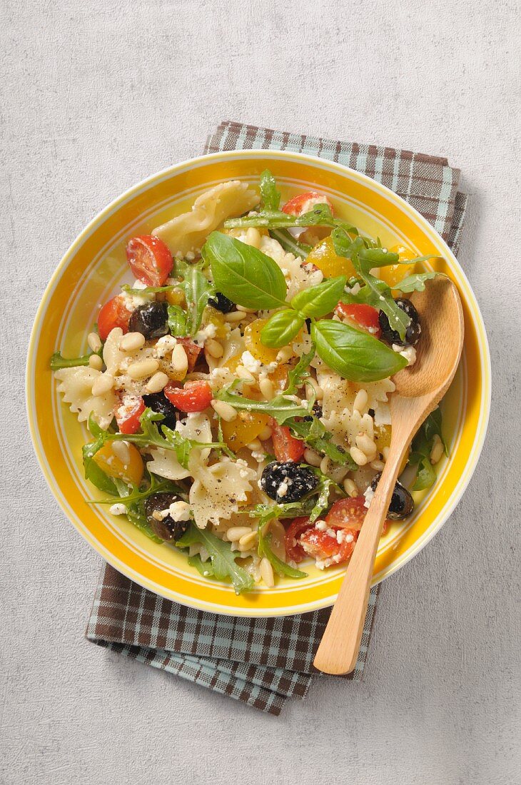 Pasta salad with cherry tomatoes, arugula, olives, ricotta and pine nuts