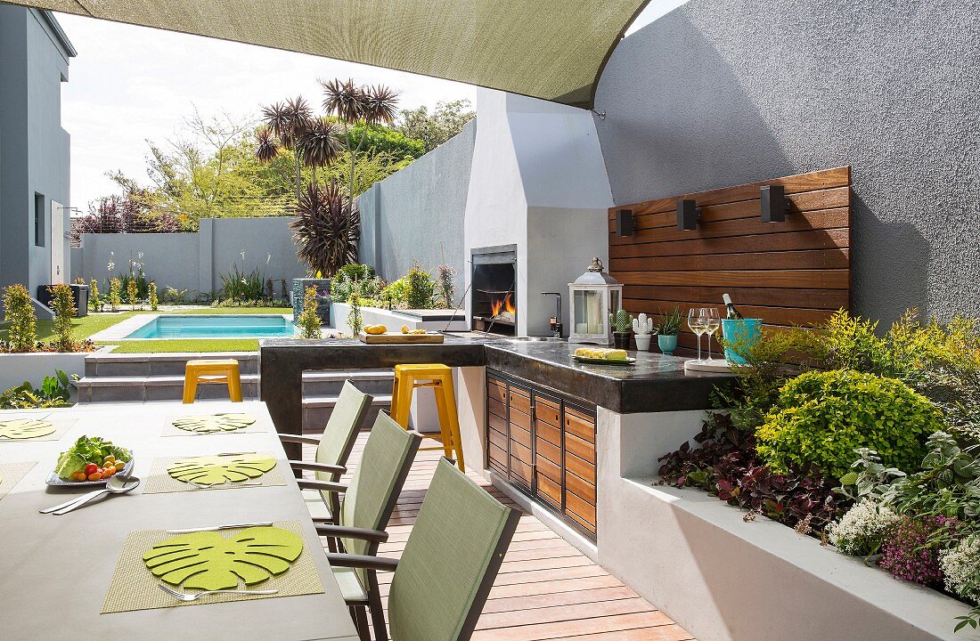 Pool, terrace and outdoor kitchen in summer garden surrounded by wall