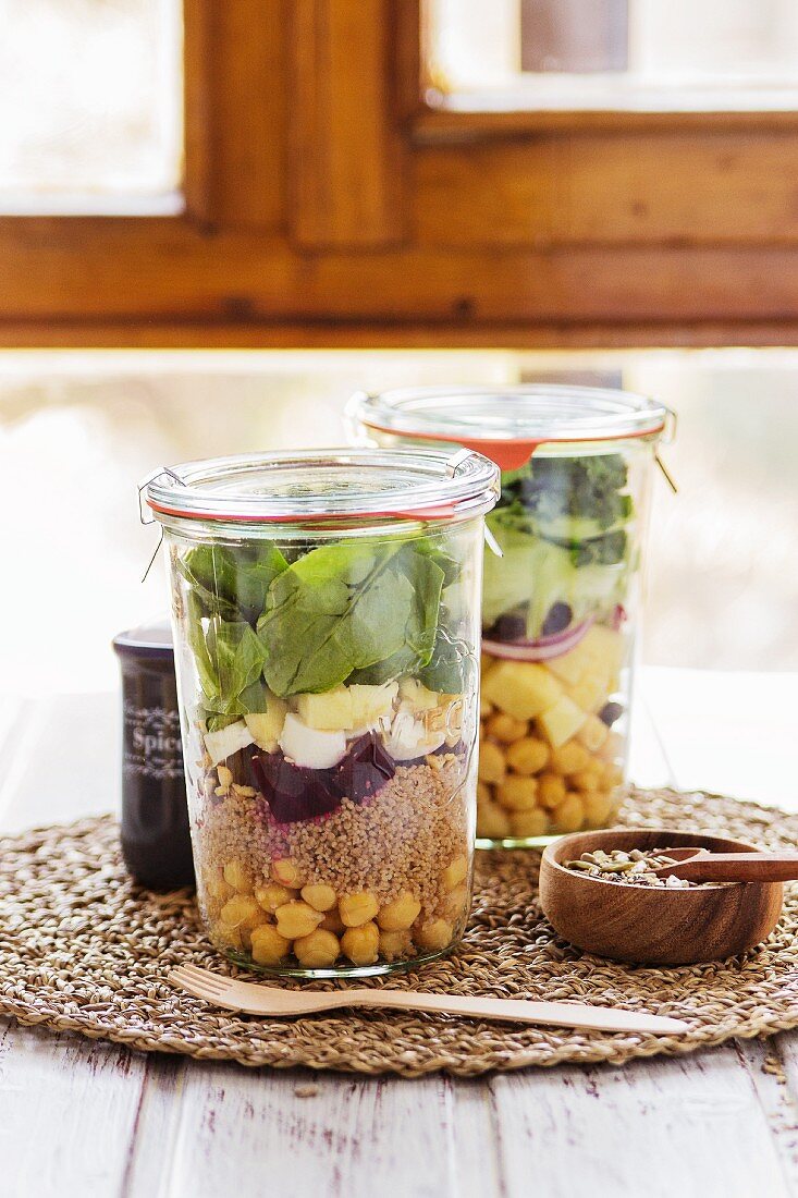 Two salads in jars prepared in a buffet service for a brunch with a mix of seeds for dressing