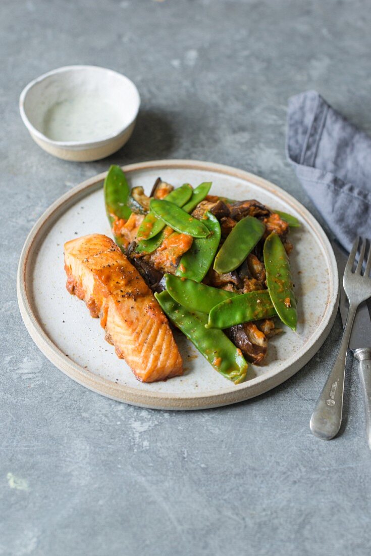 Roasted salmon fillet with roasted courgette, aubergine and green peas