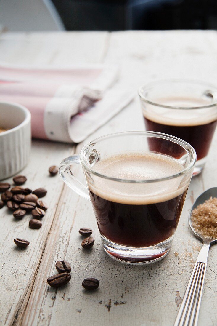 Zwei Tassen Espresso und verstreute Kaffeebohnen