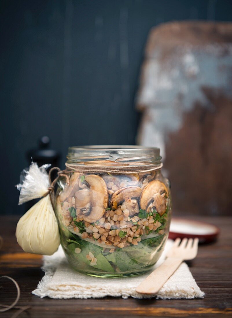 Buckwheat and spinach salad with mushrooms and vegan mayo in a glass jar