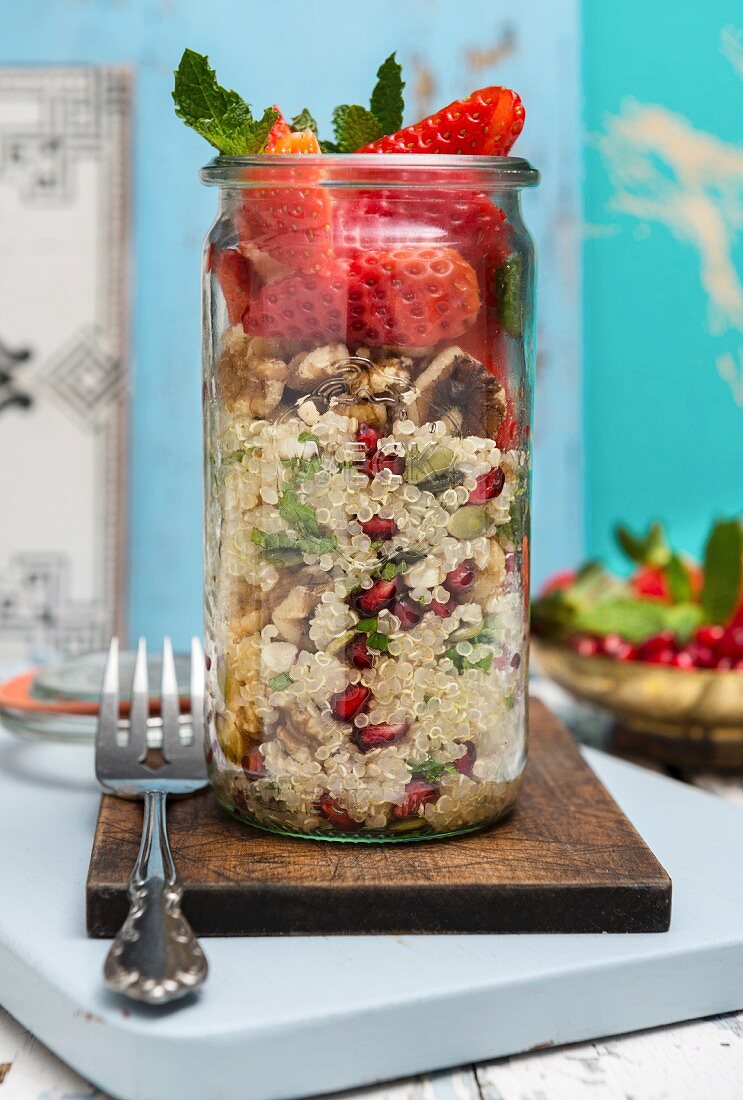 Vegan quinoa salad with wallnuts pomegranate and strawberries in a jar