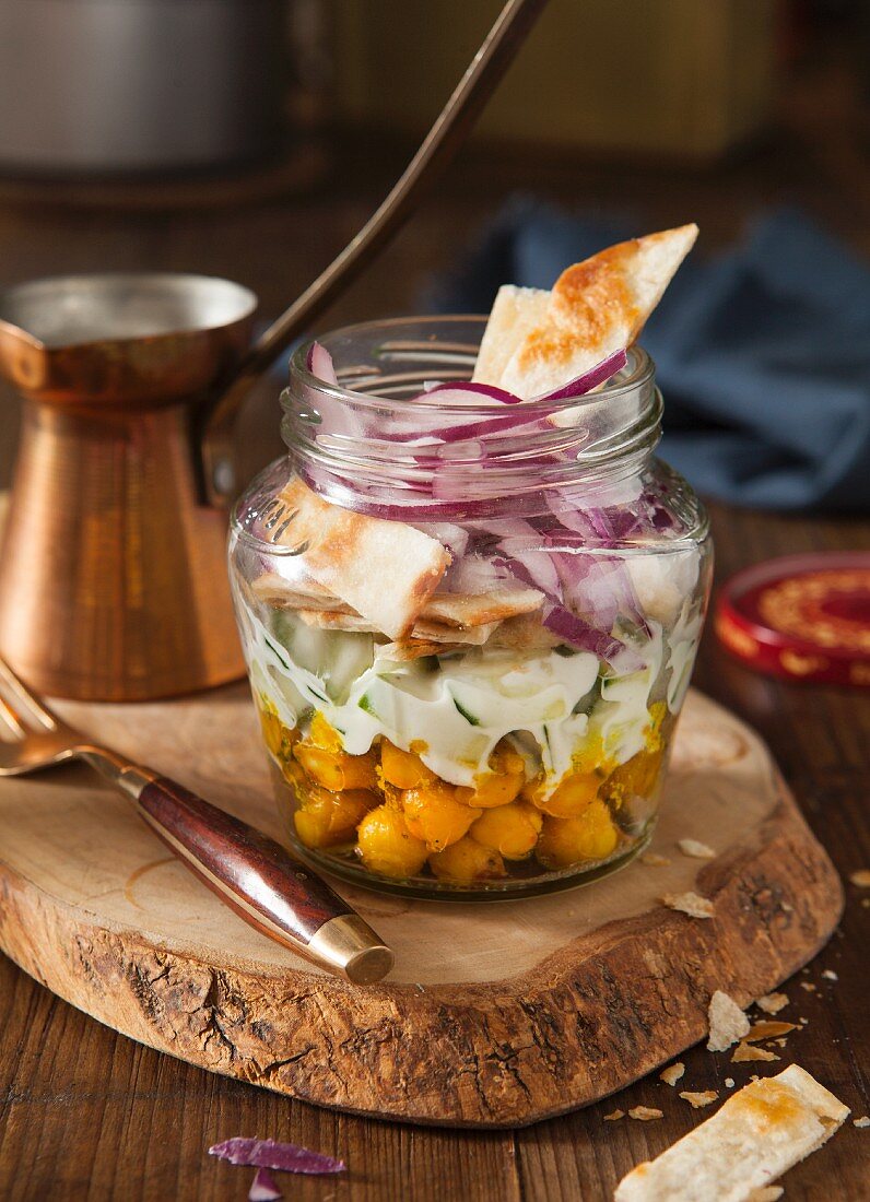 Curried chickpea packed lunch complete meal in a lunch jar on a wooden choppin board