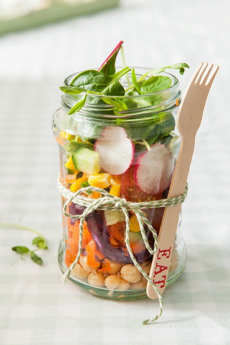 Vegetarischer Gemüsesalat im Glas mit daran gebundener Holzgabel