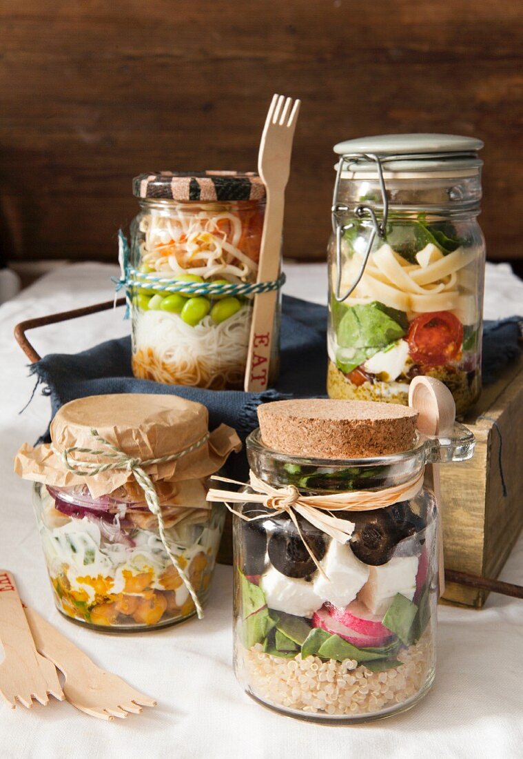 Vier verschiedene Lunchgläser mit Salaten