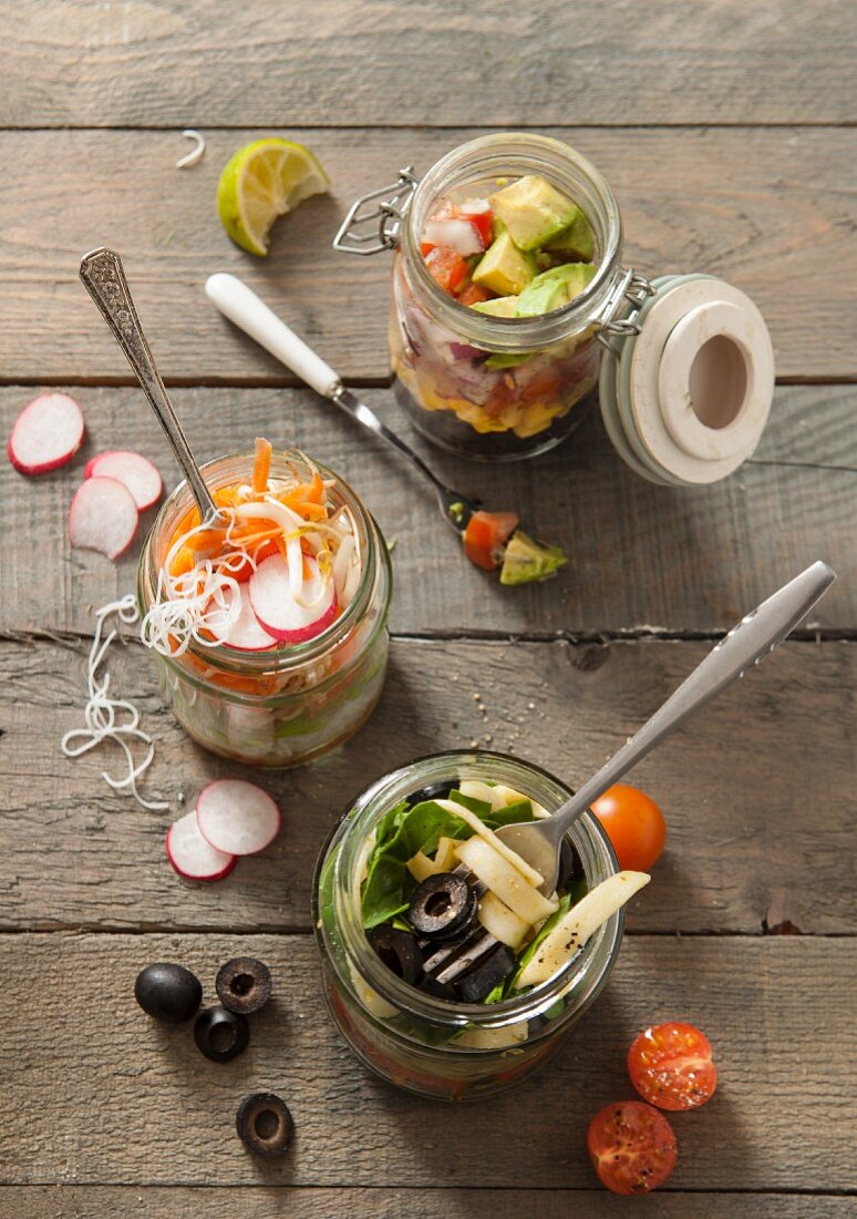 Three different lunch jar ideas with different fillings on a grey wooden table