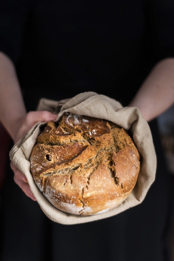 Hands holding clay pot baked beer bread