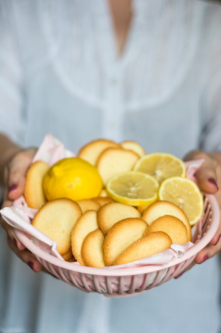 A woman holding a plastic bowl of lemon biscuits