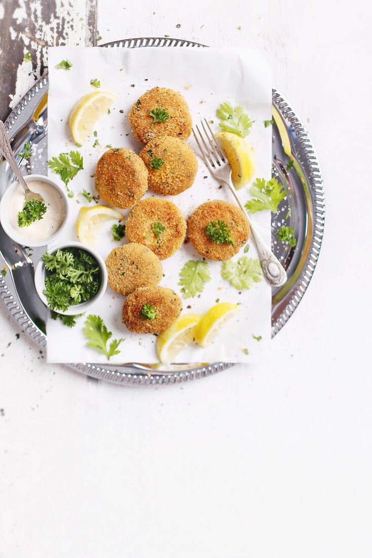 Fish Burgers with Lemon Wedges and Parsley on a white table
