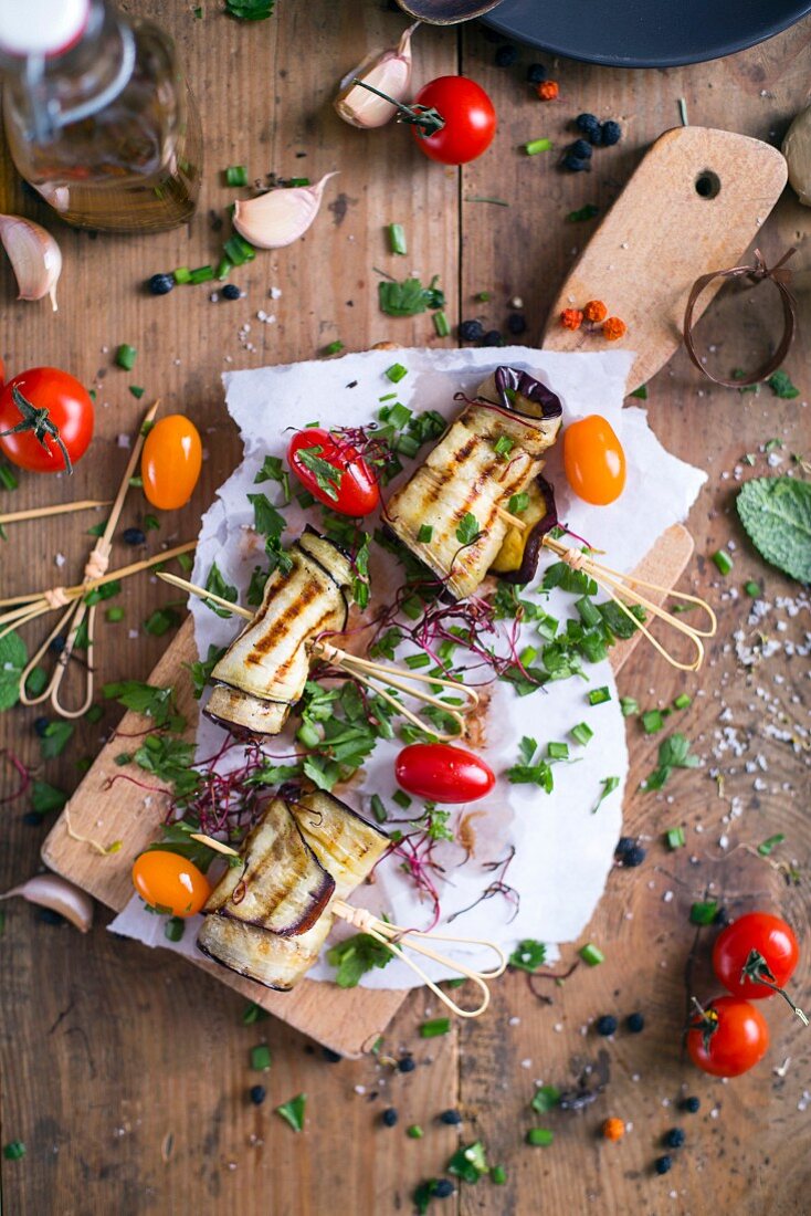 Gegrillte Auberginenröllchen mit Tomaten und Schnittlauch auf Schneidebrett