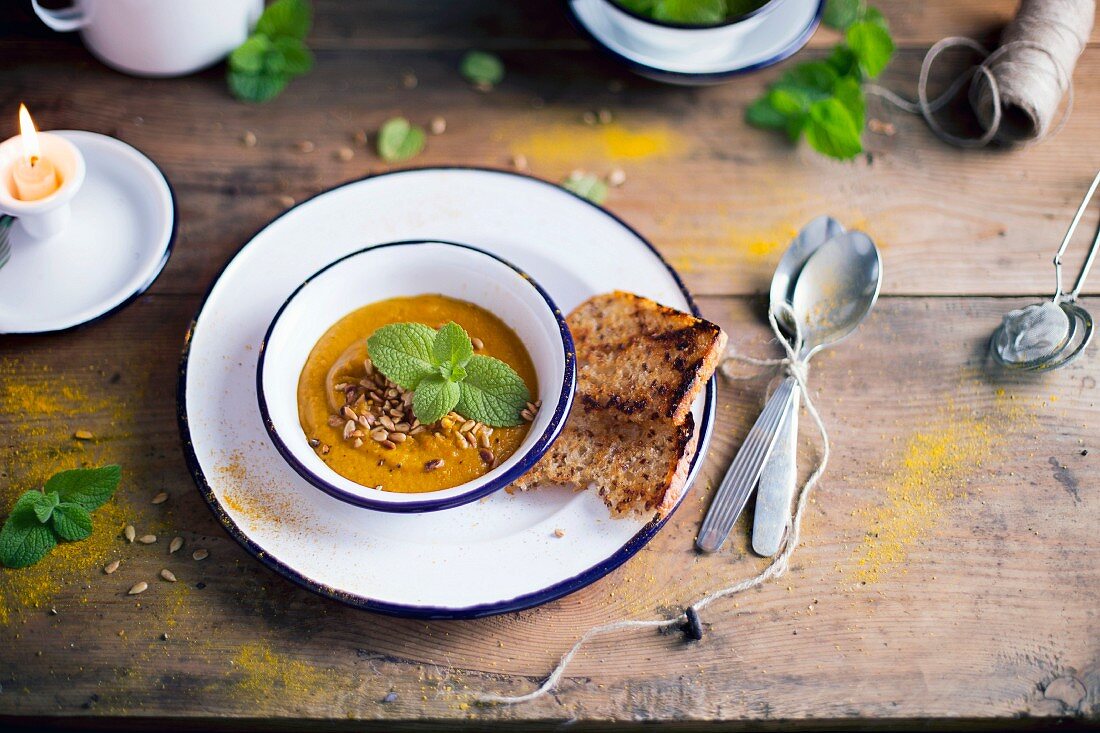 Pumpkin Carrot Soup decorated with fresh mint leaves and sunflower seeds
