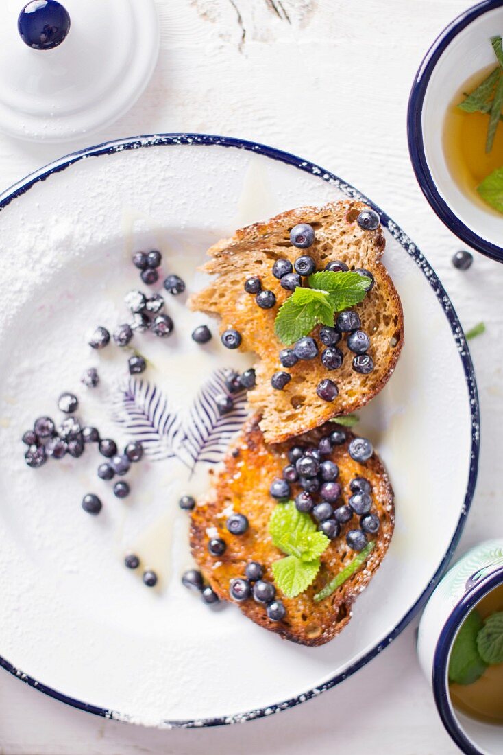 Toasts With Blueberries, Mint and Honey served on a white plate