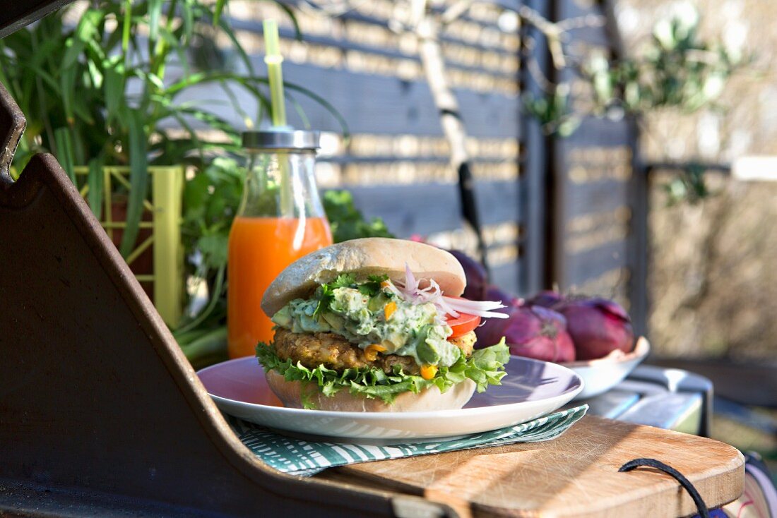Hähnchenburger mit Panko-Panade, Avocadocreme und Salat auf Tisch im Freien