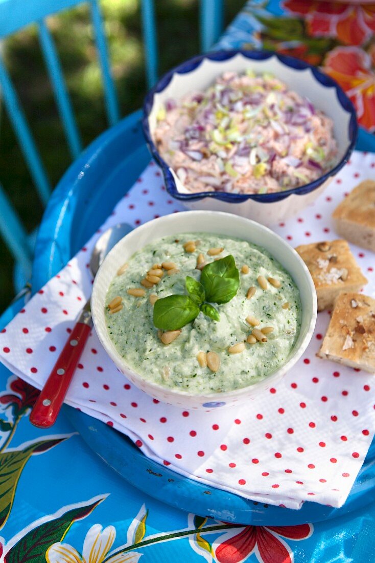 Cold basil soup with pine nuts, creamy tuna sauce and leeks on a table outdoors