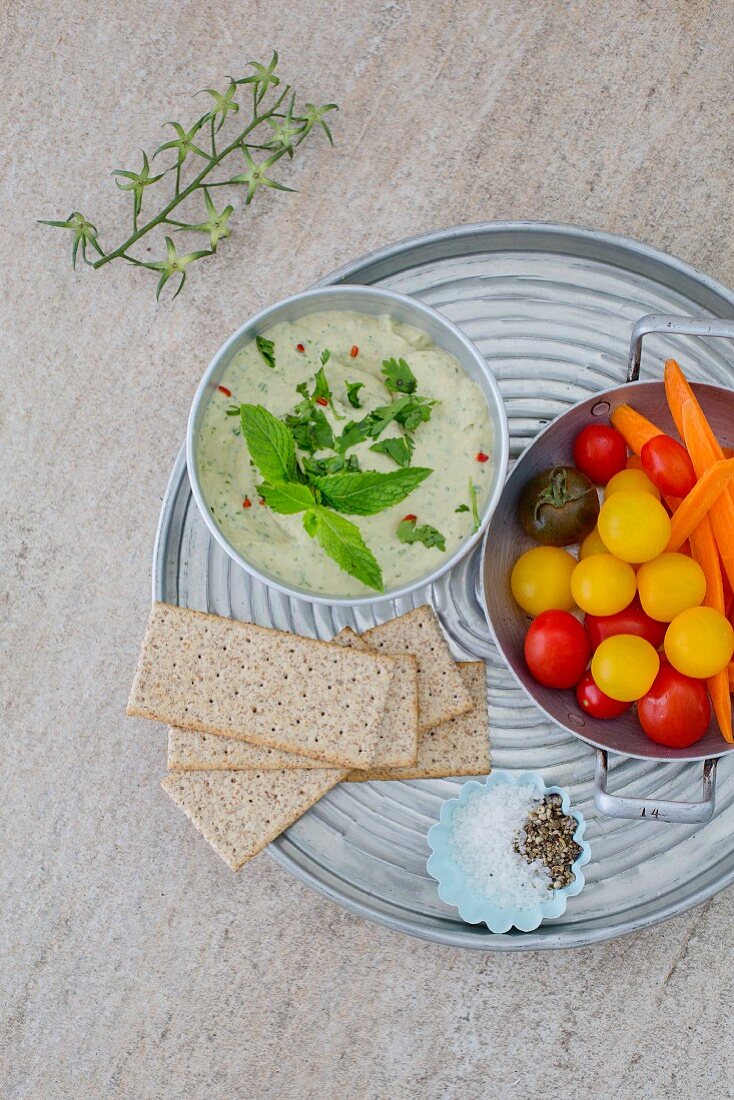 Herb houmous on a tray with colourful tomatoes and crispbread