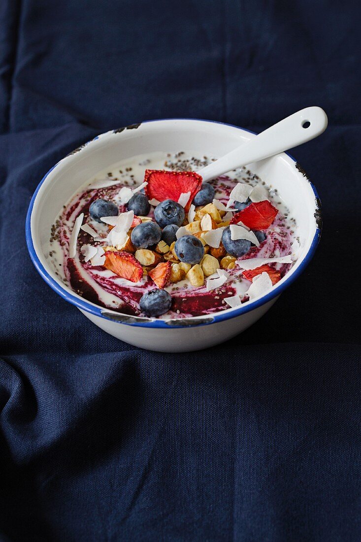 Coconut yogurt with blueberries, dried strawberries, roasted nuts and coconut chips