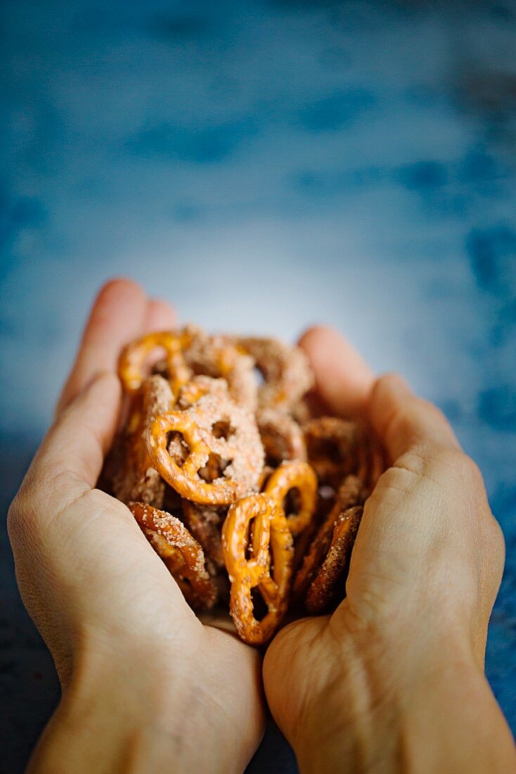 Hands holding crunchy sugar and cinnamon pretzels