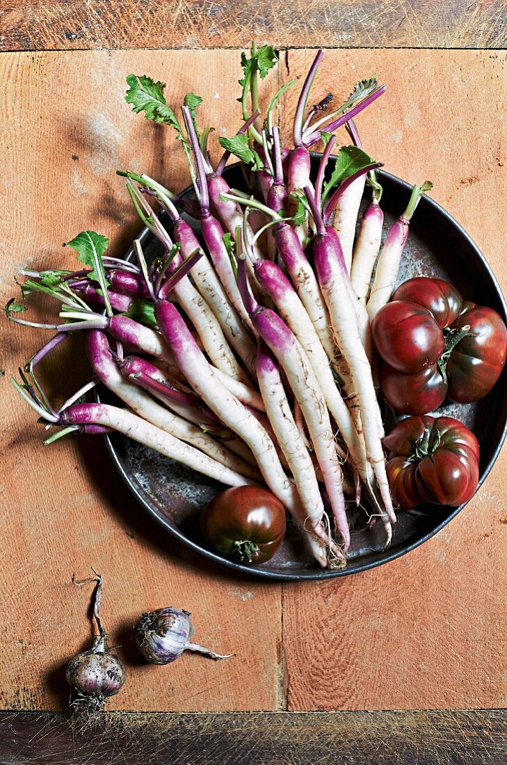 Radieschen und Tomaten in Schüssel auf Holzkiste