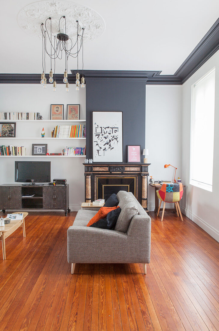 Polstersofa, Kamin. Bücherregal und Fernsehschrank im Wohnzimmer mit grauen Tönen