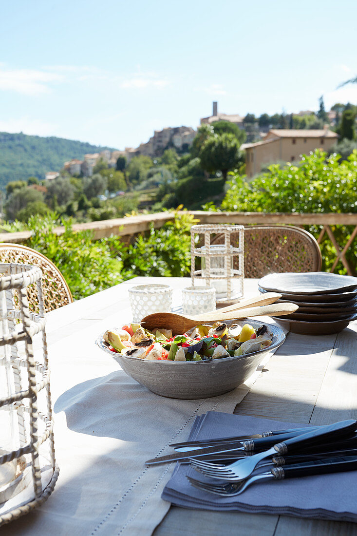 Tisch mit Salatschüssel, Besteck und Tellern auf der Dachterrasse