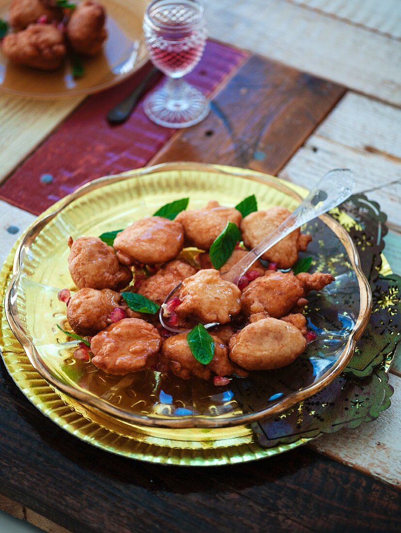 Sweet puff pastry dumplings with pomegranate seeds on a golden serving plate