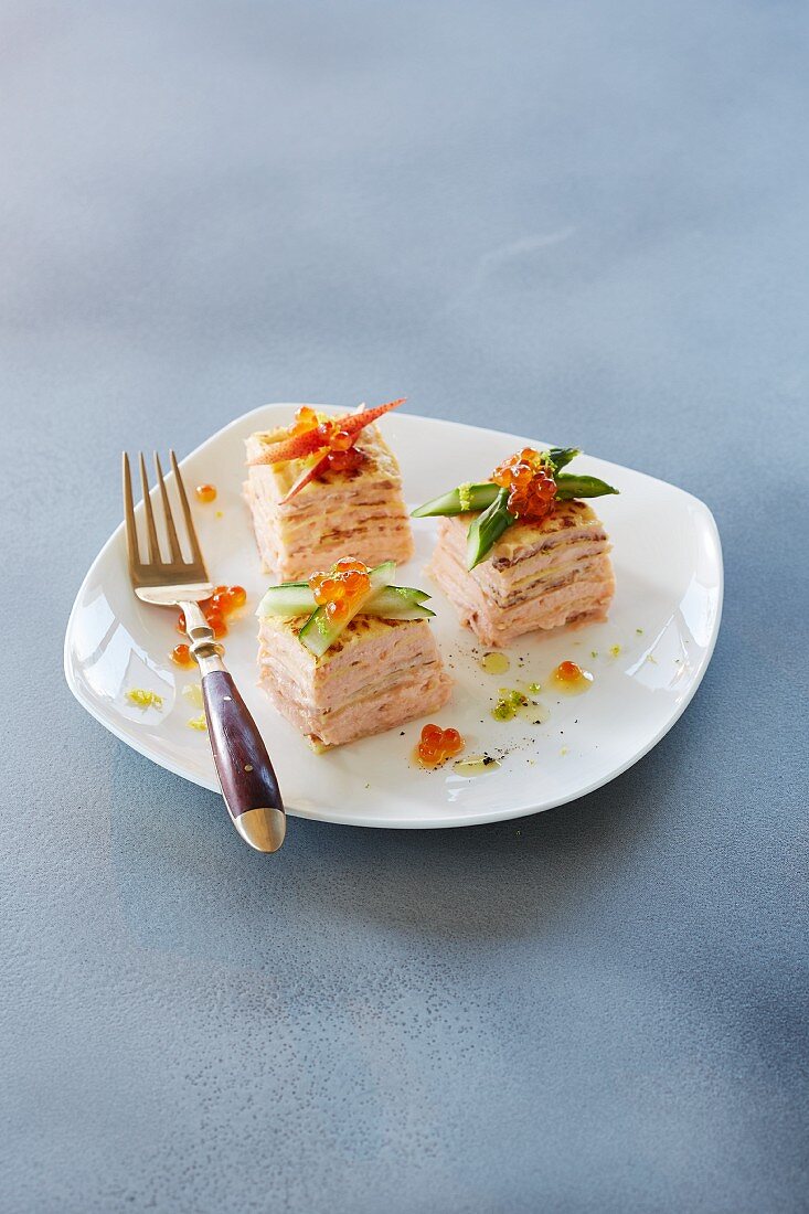 Crepe torte cubes with salmon and caviar on a plate