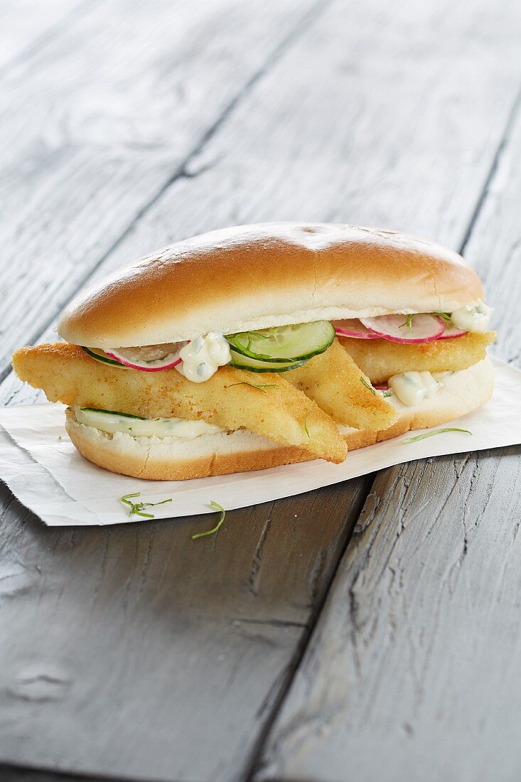 A fish finger sandwich with remoulade, cucumbers and radishes