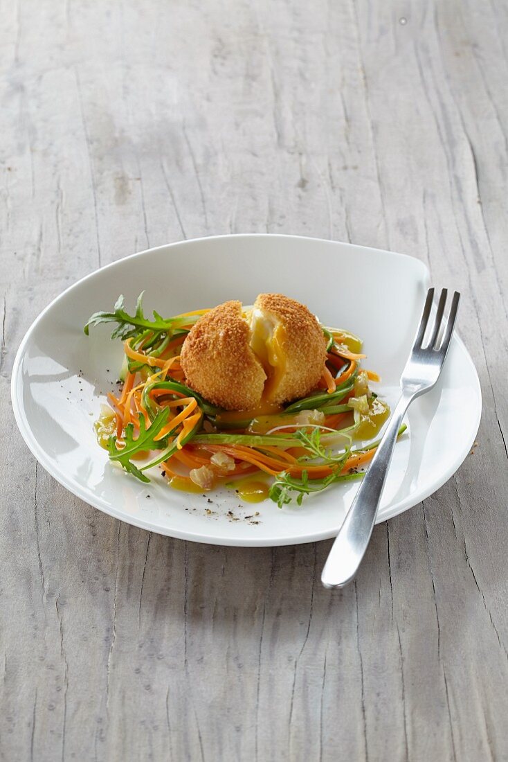 A breaded, fried egg on vegetable spaghetti