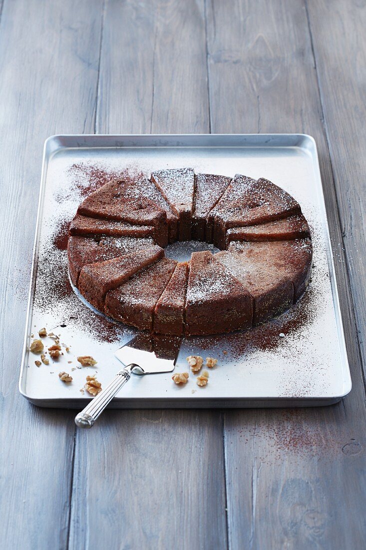 A wreath chocolate cake with nuts on a baking tray