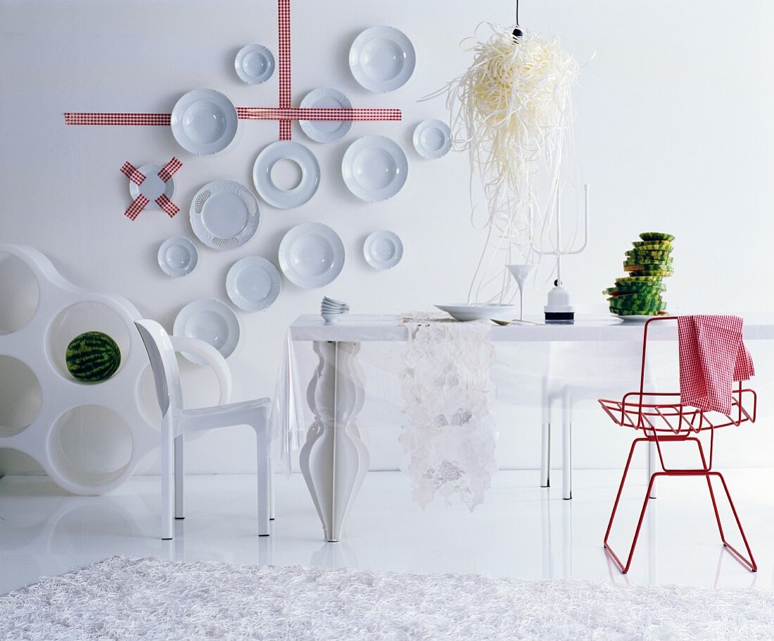 Decorative wall plates and red chair in white, futuristic dining room