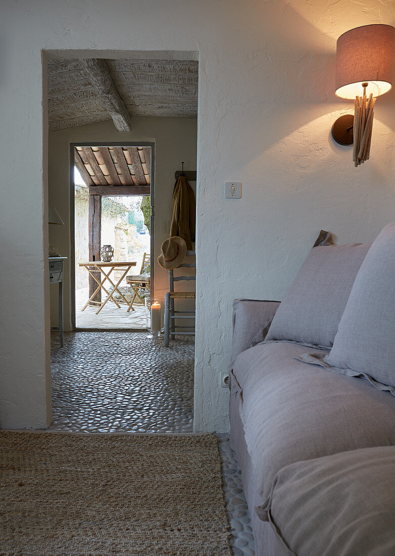 Scatter cushions on pale sofa and sconce lamp next to open doorway